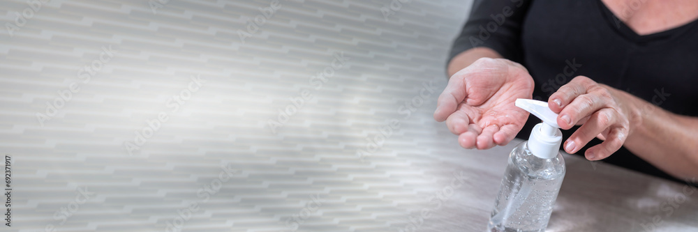 Female hand pressing on sanitizer bottle; prevention of virus and bacteria infection; panoramic banner