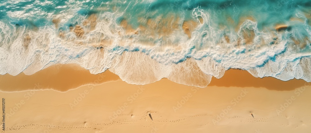 Aerial view of the foamy waves touching the sandy beach, with the serene blue ocean in the background. Aerial view of the foamy waves touching the sandy beach, with the serene blue ocean in the background.