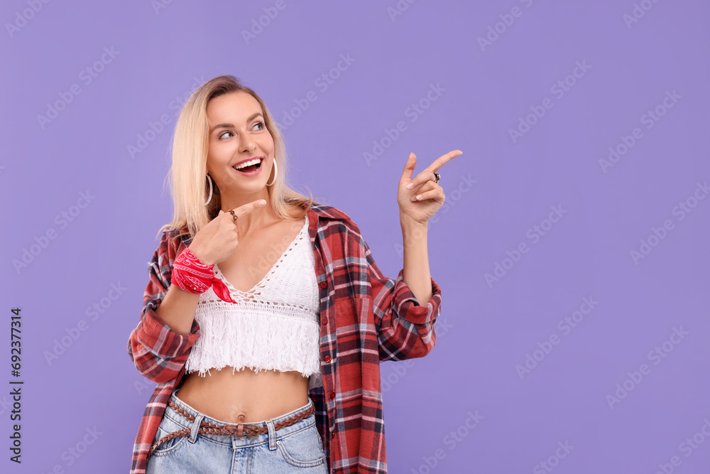 Portrait of happy hippie woman pointing at something on purple background. Space for text Portrait of happy hippie woman pointing at something on purple background. Space for text