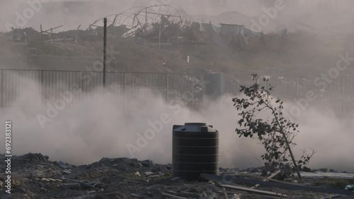 IDF military jeeps pass on a dusty road against the backdrop of buildings destroyed by Israeli missile attacks in the Gaza Strip photo