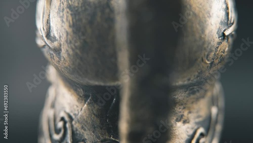 A close up macro detailed slow tilt up shot from behind of a spartan face design, warrior ancient greek bronze helmet, on a 360 rotating stand, studio lighting, 4K smooth movement photo