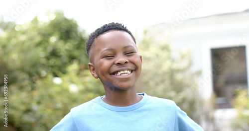 Portrait of happy african american boy laughing in sunny garden, slow motion photo