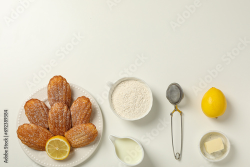 Madeleine cakes, cream, flour, butter and lemon on white background, space for text photo