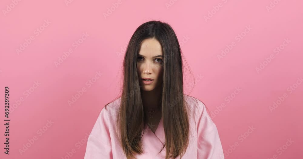 Brunette woman threatens with a fist is isolated on pink background, shows fist has annoyed face expression going to revenge or threaten someone makes serious look. I will show you who is boss. Brunette woman threatens with a fist is isolated on pink background, shows fist has annoyed face expression going to revenge or threaten someone makes serious look. I will show you who is boss.
