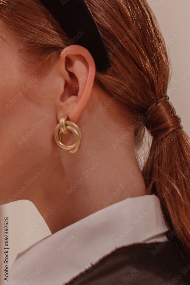 Stylish small golden round earring in the women's ear