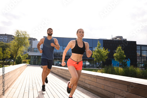 Healthy lifestyle. Happy couple running outdoors on sunny day, low angle view