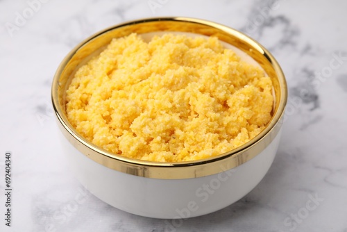 Tasty cornmeal in bowl on white marble table, closeup