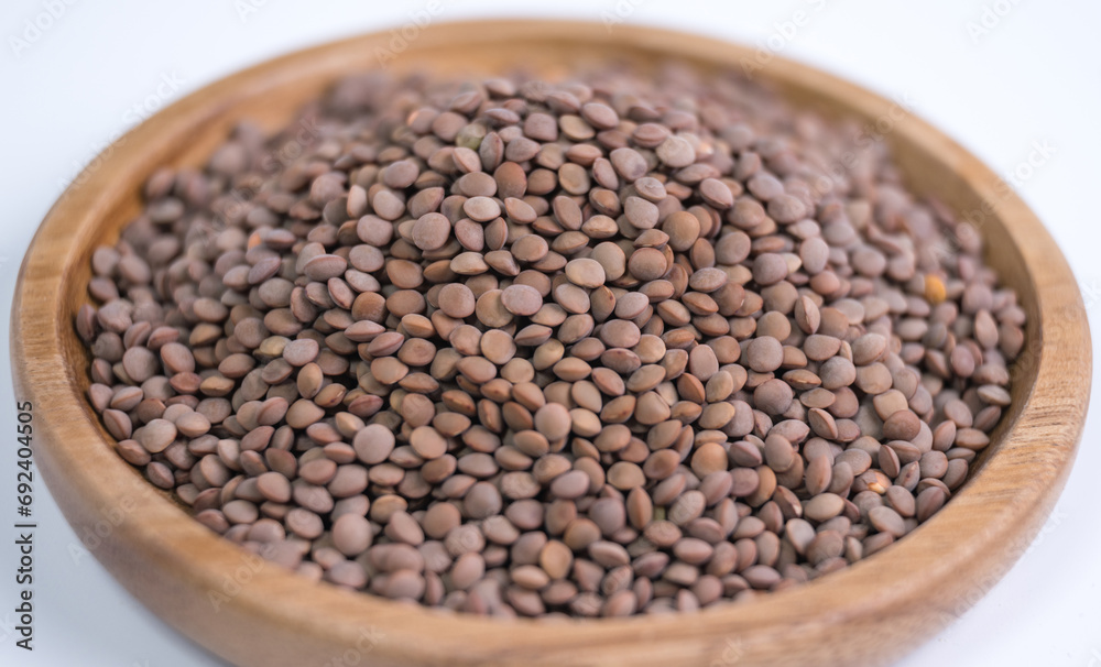 Lentils, beans, wooden plate, close-up, white background Lentils, beans, wooden plate, close-up, white background
