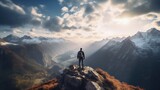 A man stands on top of a mountain and looks at a breathtaking panoramic view of the mountains. The concept of goals and achievements