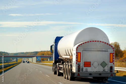 Dangerous goods transportation by semi truck with propane tank. The tank truck has a side view and shows hazard labels for high-temperature liquid and miscellaneous hazards. The truck follows the ADR photo