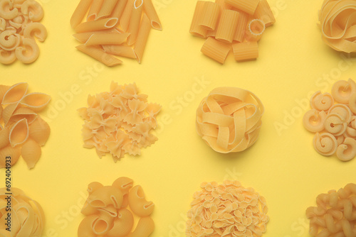 Different types of pasta on yellow background  flat lay