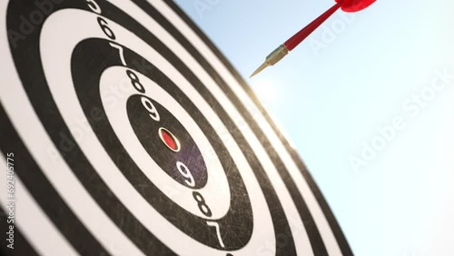 Slow motion of Red Arrow darts shoots on center point of dartboard on blue sky background. 3D animation. Idea concept. Selective focus.