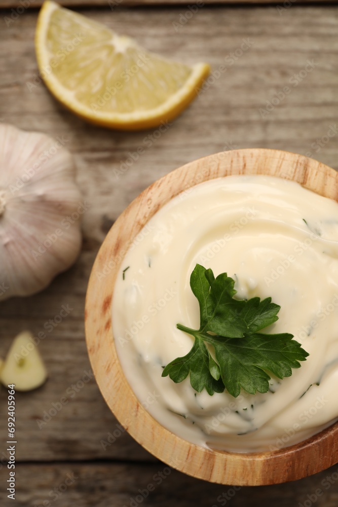 Tasty sauce with garlic, parsley and lemon on wooden table, flat lay Tasty sauce with garlic, parsley and lemon on wooden table, flat lay