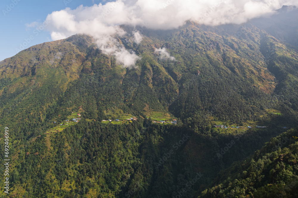 Naklejka premium Terraced farming in Nepal. Village on a terraced hill during trekking through Kari la pass on EBC or Three passes trek in Himalayas.