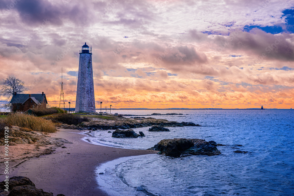 New Haven Landmark Lighthouse at the beachfront of Morgan Point Park, built in 1847 in Connecticut. Winter coastal landscape of New England with dramatic clouds, and glacial rocks.
