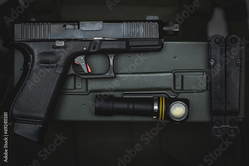 Tactical equipment and weapons, pistol with threaded barrel for suppressor, flashlight and multitool.