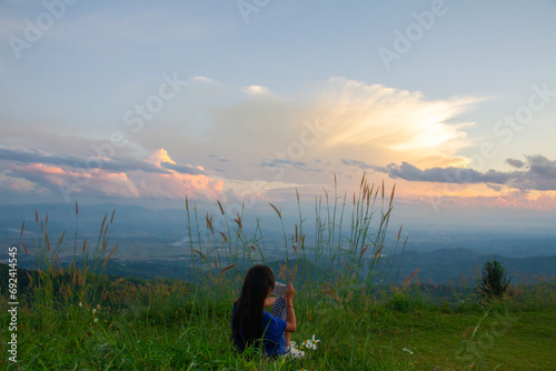 A girl holds a phone and takes a photo of the mountain, landscape and sky background concept, nature of north Thailand, fog-laden valleys. photo