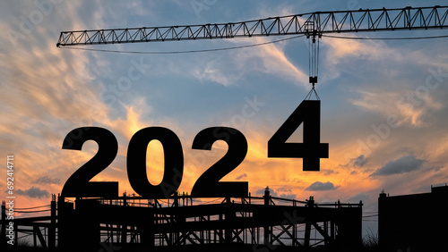 crane lifting number 4 come down to 2024 , prepare for welcome beginning new year 2024 with silhouette construction site , sunrise sky at background for start and reach new goals for year 2024.