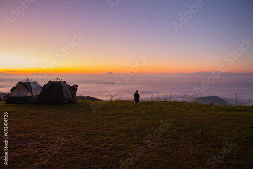 A girl sitting and looking at the sea of mist in the morning, landscape and sky background concept, nature of north Thailand,, top view on the mountain sunrise and sunset. photo