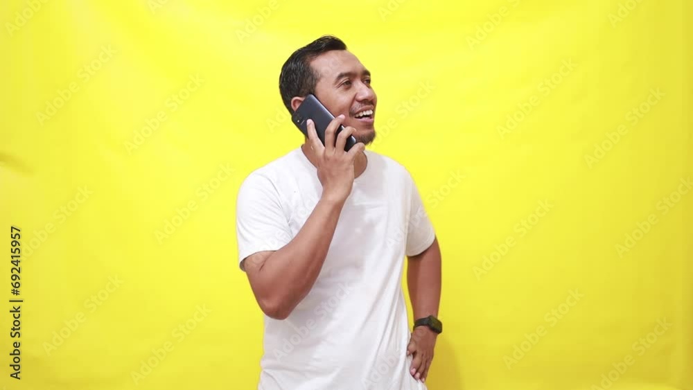 Adult handsome man over isolated yellow background keeping a conversation with the mobile phone Adult handsome man over isolated yellow background keeping a conversation with the mobile phone