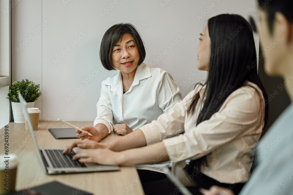 Shot of senior business woman talking or explaining marketing strategy to younger colleagues. Shot of senior business woman talking or explaining marketing strategy to younger colleagues.