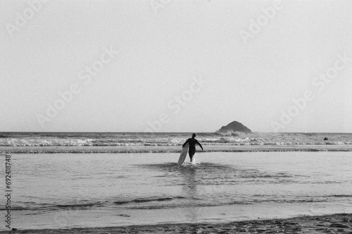 surfer on the beach running towards the waves