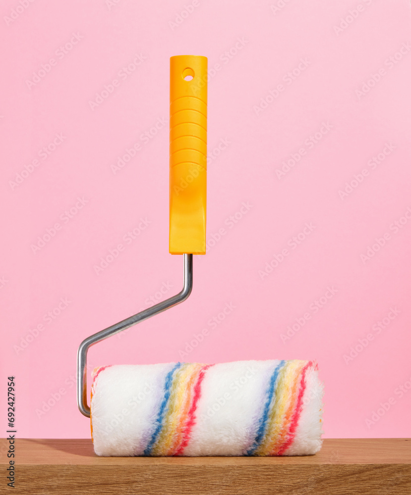 Obraz premium Paint roller on a pink background. Home improvement and construction tools. Renovation concept.