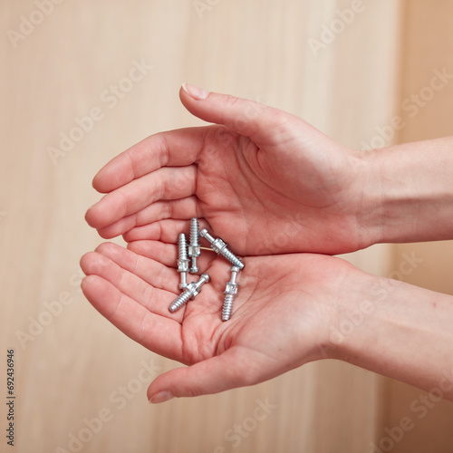 Female hands holding the screws in their hands. Concept for self-contained, easy furniture assembly.