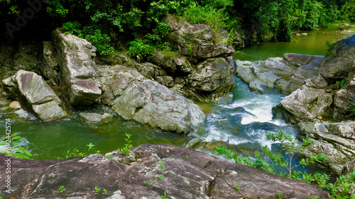 Mountain river in the jungle. The flow of a mountain river moves over the stones, forming a cascading waterfall, among the humid tropical forest.