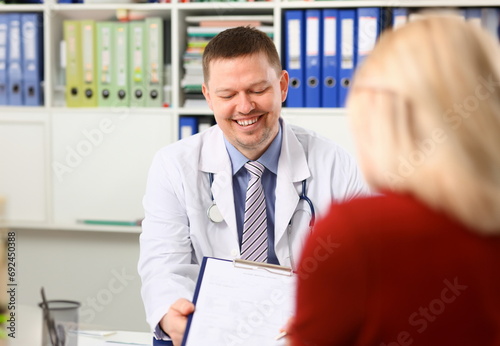 Handsome smiling male doctor talk with patient about his history list. Physical exam er anamnesis communication disease prevention ward round 911 prescribe remedy healthy lifestyle concept