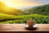Coffee cup or tea on wooden table over tea plantation background at sunset, copy space