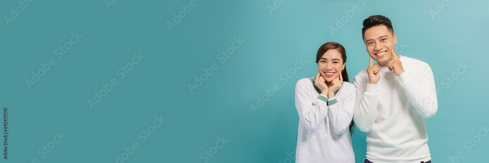 Optimistic young couple keeping hands near cheeks and looking at camera in happiness Optimistic young couple keeping hands near cheeks and looking at camera in happiness