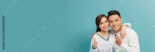 happy casual couple pointing up to something on blue background
