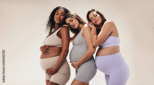 Group of pregnant mothers leaning on each other in a prenatal fitness class photo