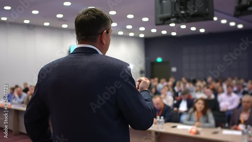 Speaker man with microphone at seminar audience at stage, business people, conference, meeting, congress, coach, speaker, business forum, training, seminar, speech person about management, economics photo