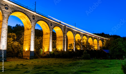 Panoramic view of “Bekeviadukt“ bridge in Altenbeken Germany (1853). Historic railway viaduct on the main line Paderborn Warburg is a monument. Illumination at blue hour twilight from below the bridge