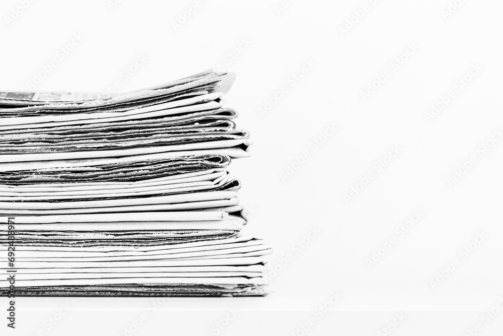 a stack of newspapers on a table on a white background with a copy space, black and white photo