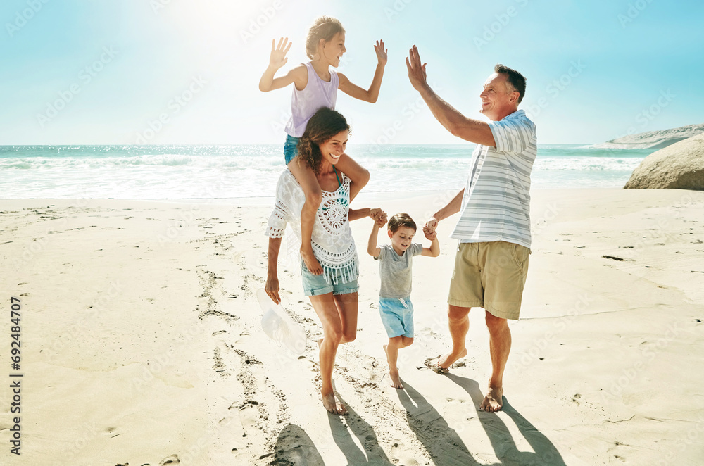 Parents, children and beach for high five happy or summer travel vacation, ocean sunshine or family development. Man, woman and kids on sand for holiday relax walking or outdoor, clean air or smile