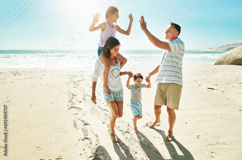 Parents, children and beach for high five happy or summer travel vacation, ocean sunshine or family development. Man, woman and kids on sand for holiday relax walking or outdoor, clean air or smile