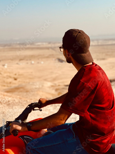 Teenager boy riding 4 weal scoter in the desert 