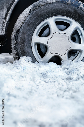 Closeup shot of an automobile wheel stuck in deep snow photo