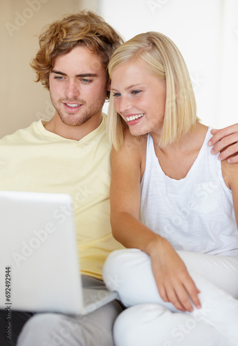 Laptop, love and happy couple relax in a house streaming movies, video or film, show or social media together. Tech, search and people in living room with online entertainment for weekend or vacation © Tabitha Rose/peopleimages.com