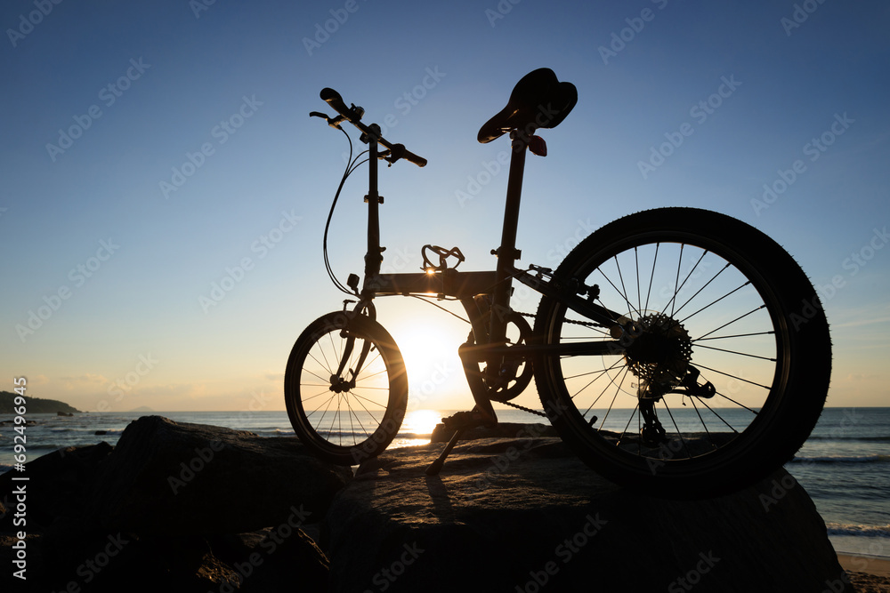 Obraz premium A folding bike on sunrise seaside rocks