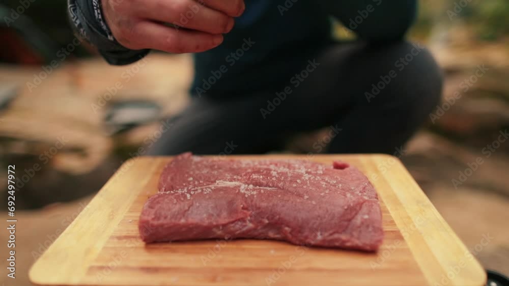 Close-up of a beef steak on a wooden board with salt falling on it. Marinating meat in the open air. Close-up of a beef steak on a wooden board with salt falling on it. Marinating meat in the open air.