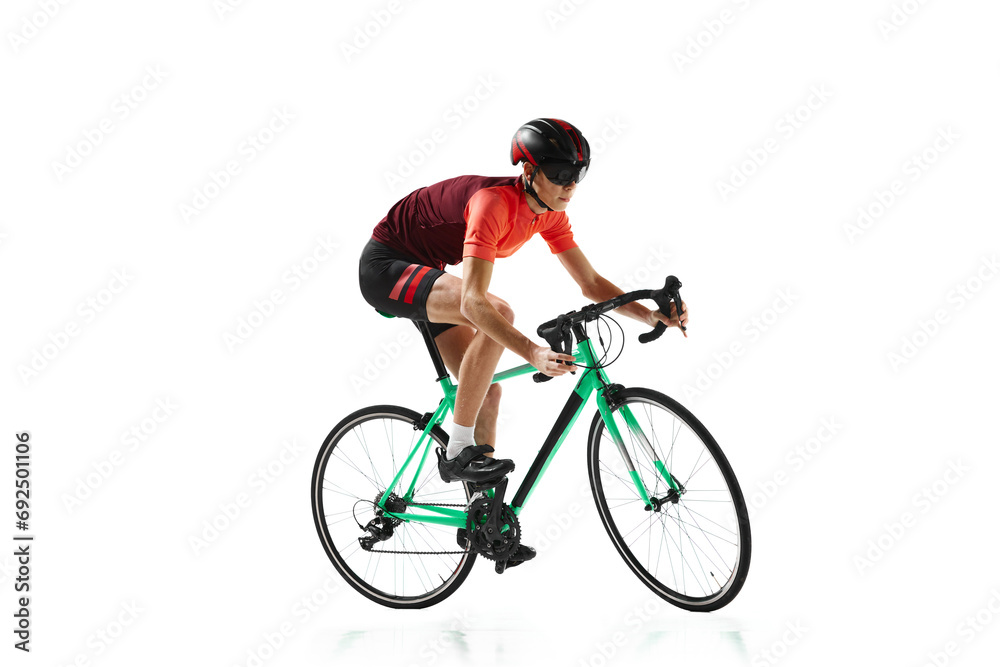 Muscular young man, athlete, cyclist in uniform and helmet, riding bicycle isolated over white studio background Muscular young man, athlete, cyclist in uniform and helmet, riding bicycle isolated over white studio background