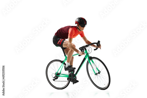 Fototapeta Naklejka Na Ścianę i Meble -  Muscular young man, athlete, cyclist in uniform and helmet, riding bicycle isolated over white studio background