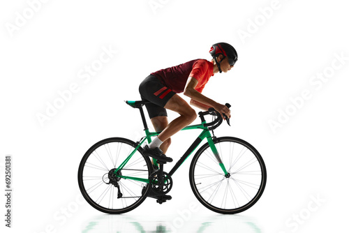 Concentrated young man, cycling athlete in sportswear and helmet riding bicycle, training isolated over white studio background