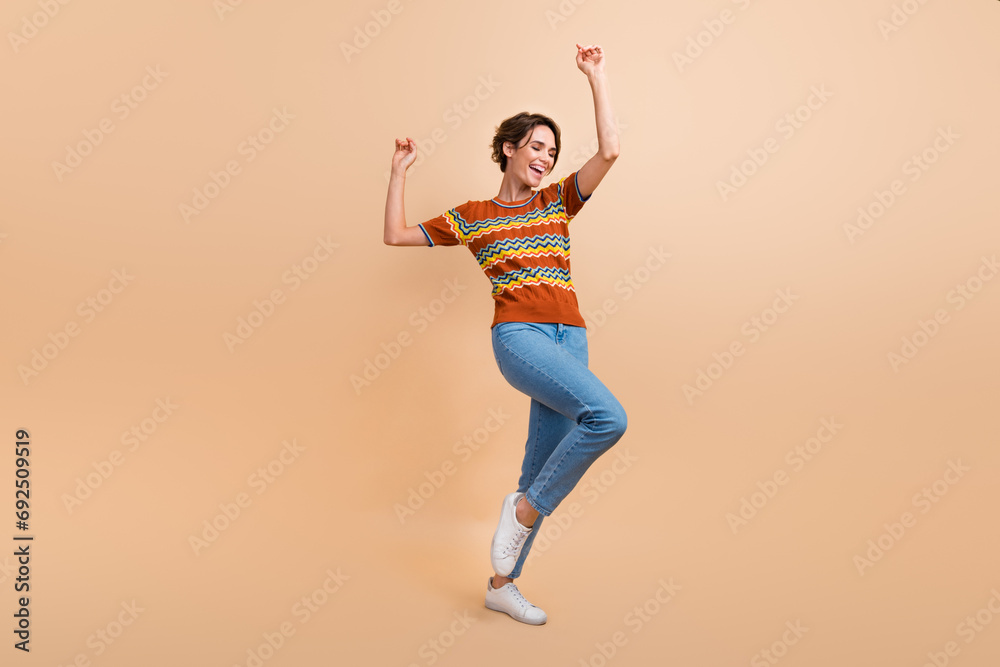 Full body photo of cute cheerful young lady raise hands enjoy dancing clubbing isolated on beige color background Full body photo of cute cheerful young lady raise hands enjoy dancing clubbing isolated on beige color background