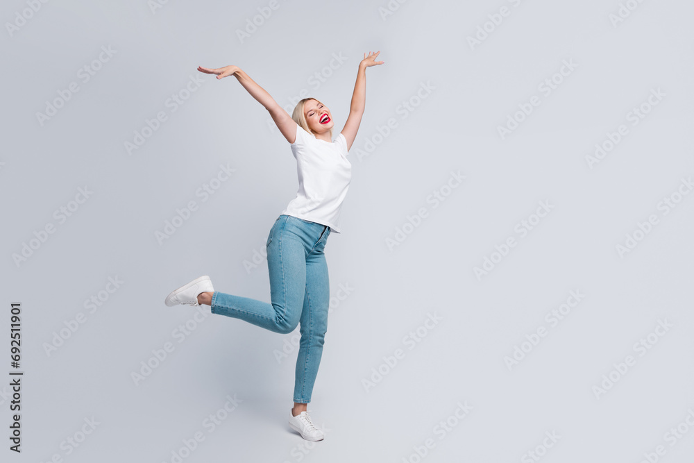 Full length photo of good mood cute girl dressed white t-shirt denim pants rasing hands up like wings isolated on gray color background