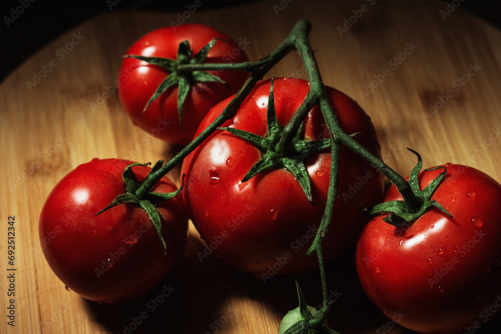 A branch of ripe red organic tomatoes on a wooden board. Background. Vegetables and harvest. High quality photo